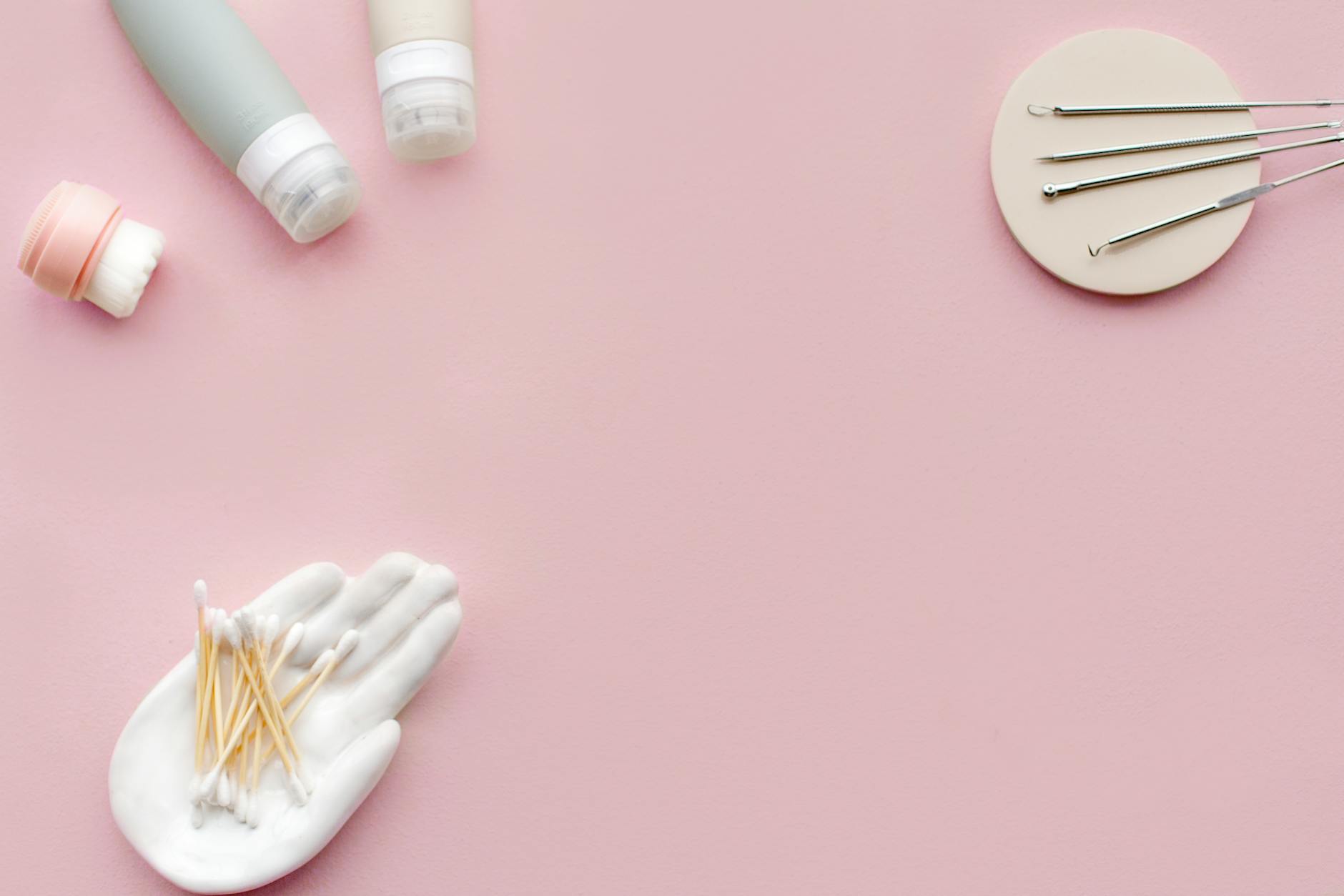 variety of cosmetic tools and products on pink surface